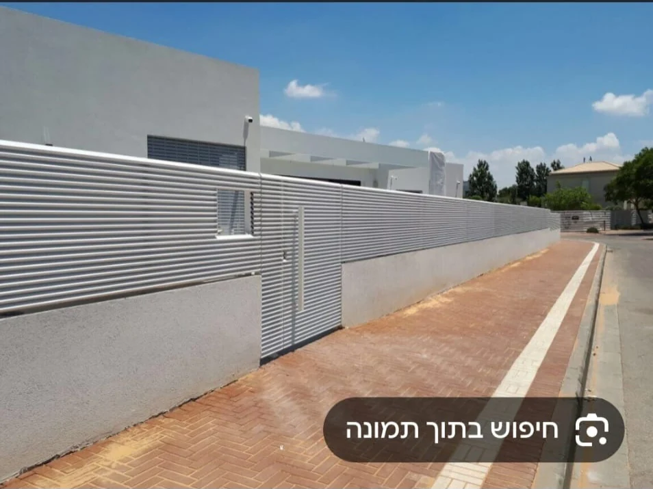 גדר פסים בהירה ושער כניסה לאורך קיר חיצוני — ענק הצל